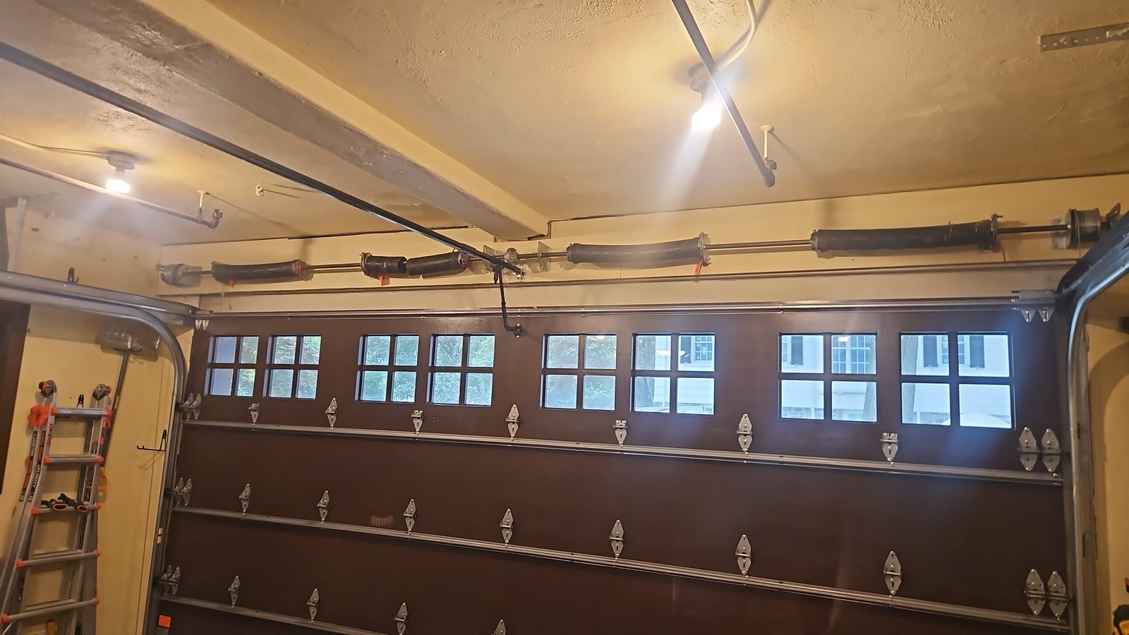 Interior view of a dark carriage-style garage door with the torsion spring system