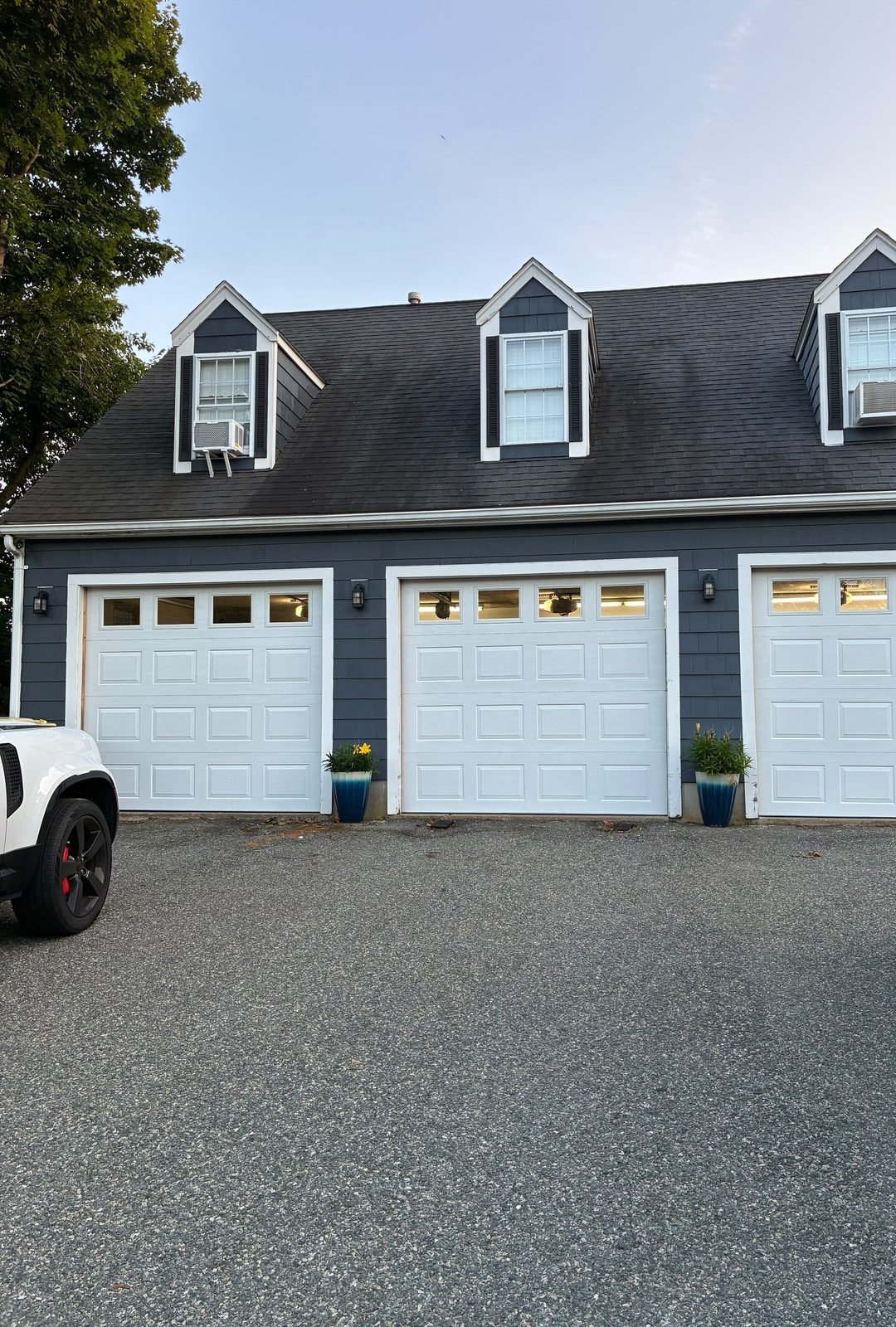 Garage doors after replacement — new white doors with windows on a navy-sided home