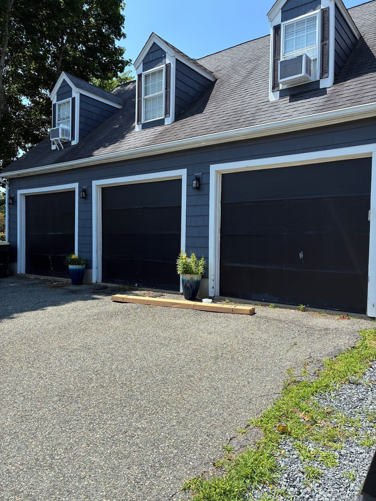 Garage doors before replacement — worn dark doors on a navy-sided home