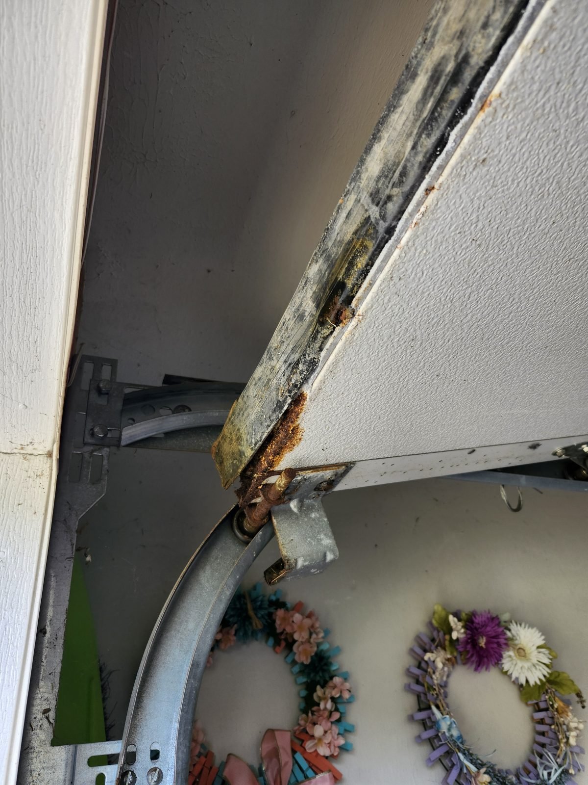 Worn garage door bottom seal and rusted roller before replacement in Randolph, MA
